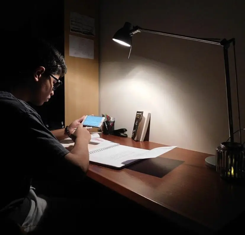 Charaf as a teenager at his desk under a lamp at night in Qatar