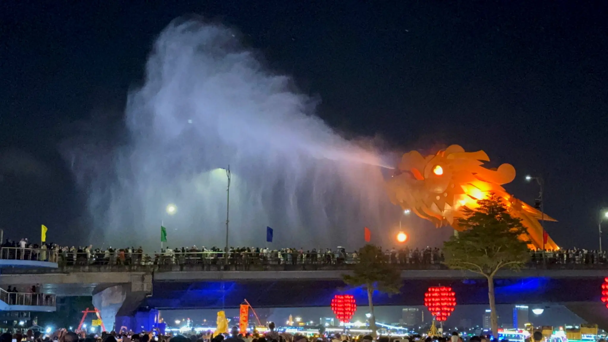 Dragon Bridge spraying water at night above crowds lining the bridge