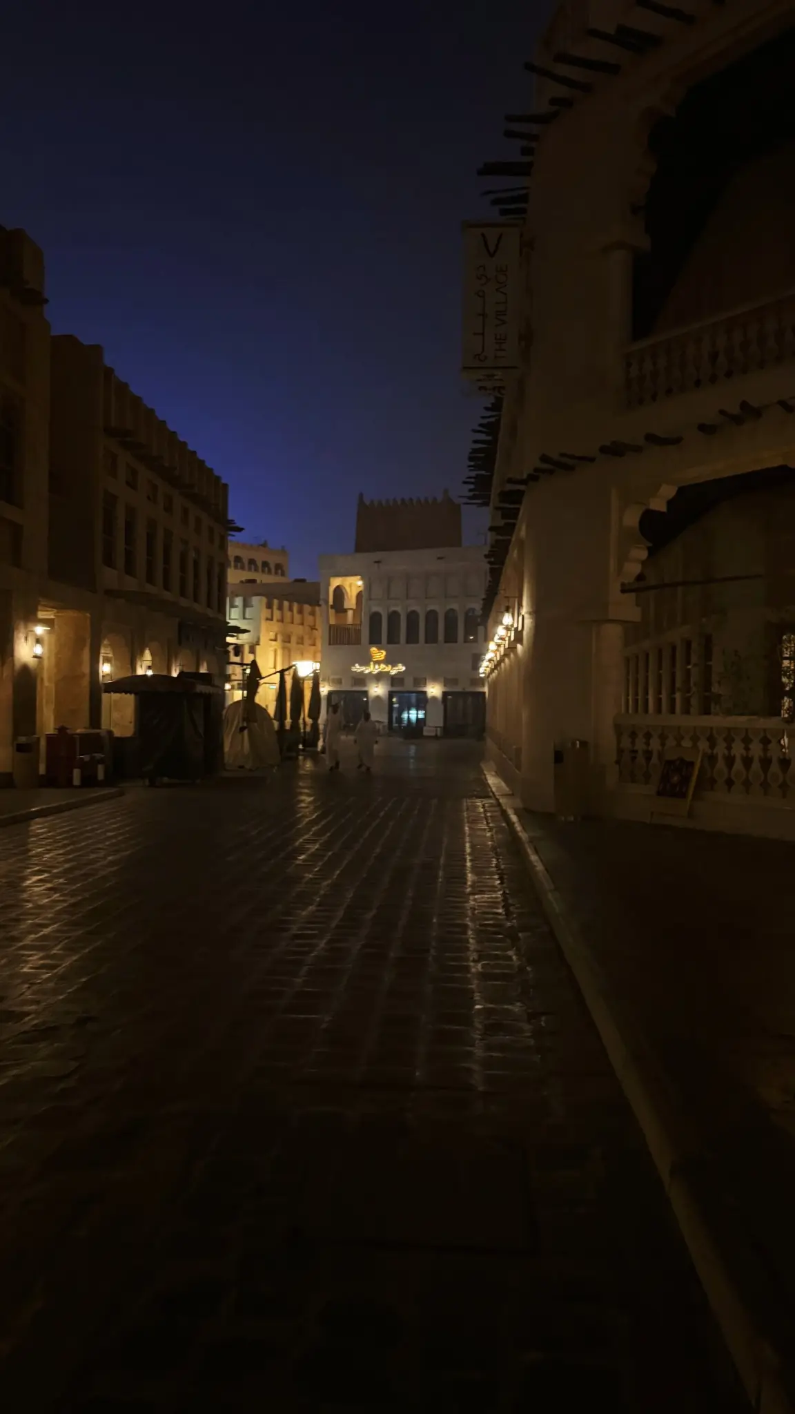 Quiet stone-paved lane of Souq Waqif lit by warm lamps at night
