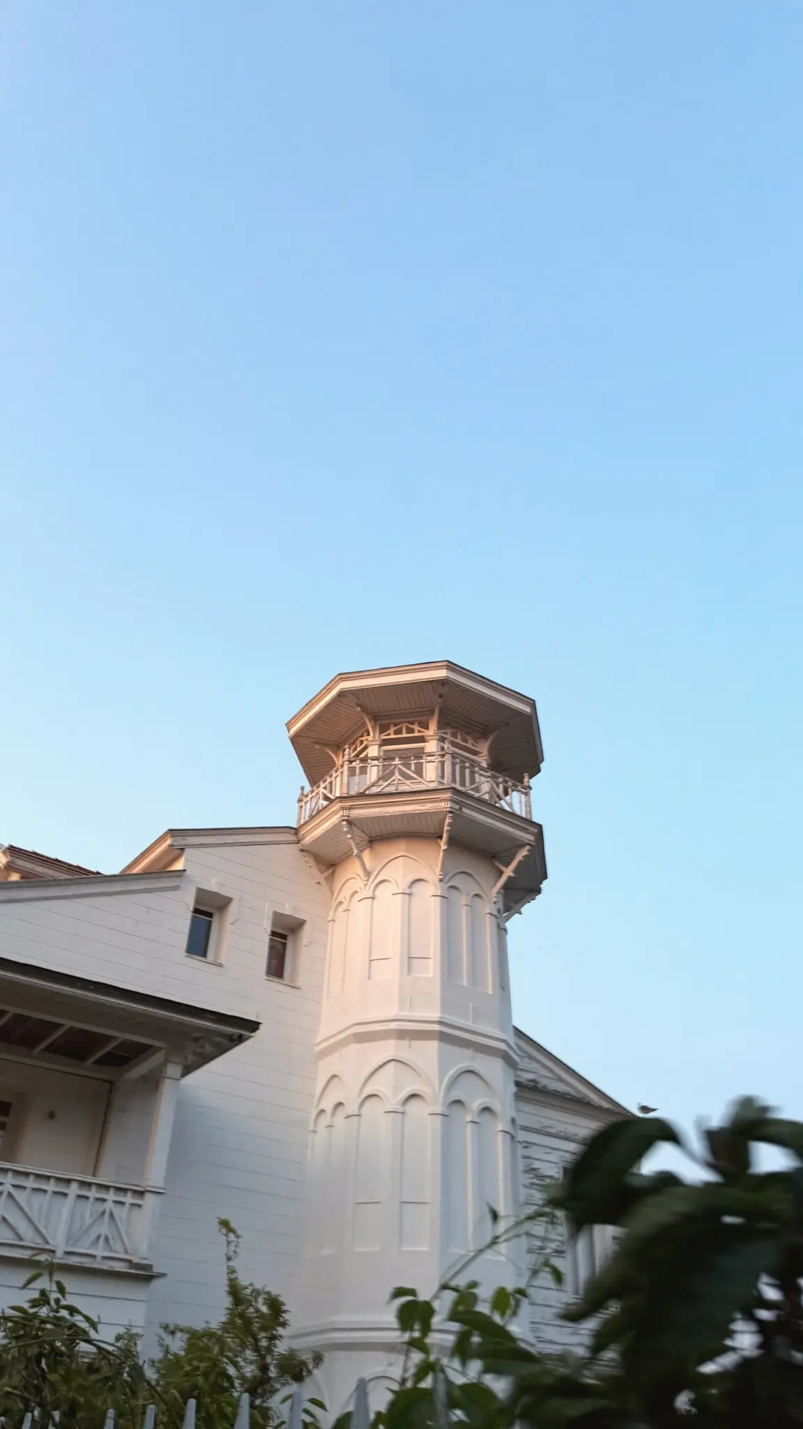White wooden house with an octagonal tower in soft evening light