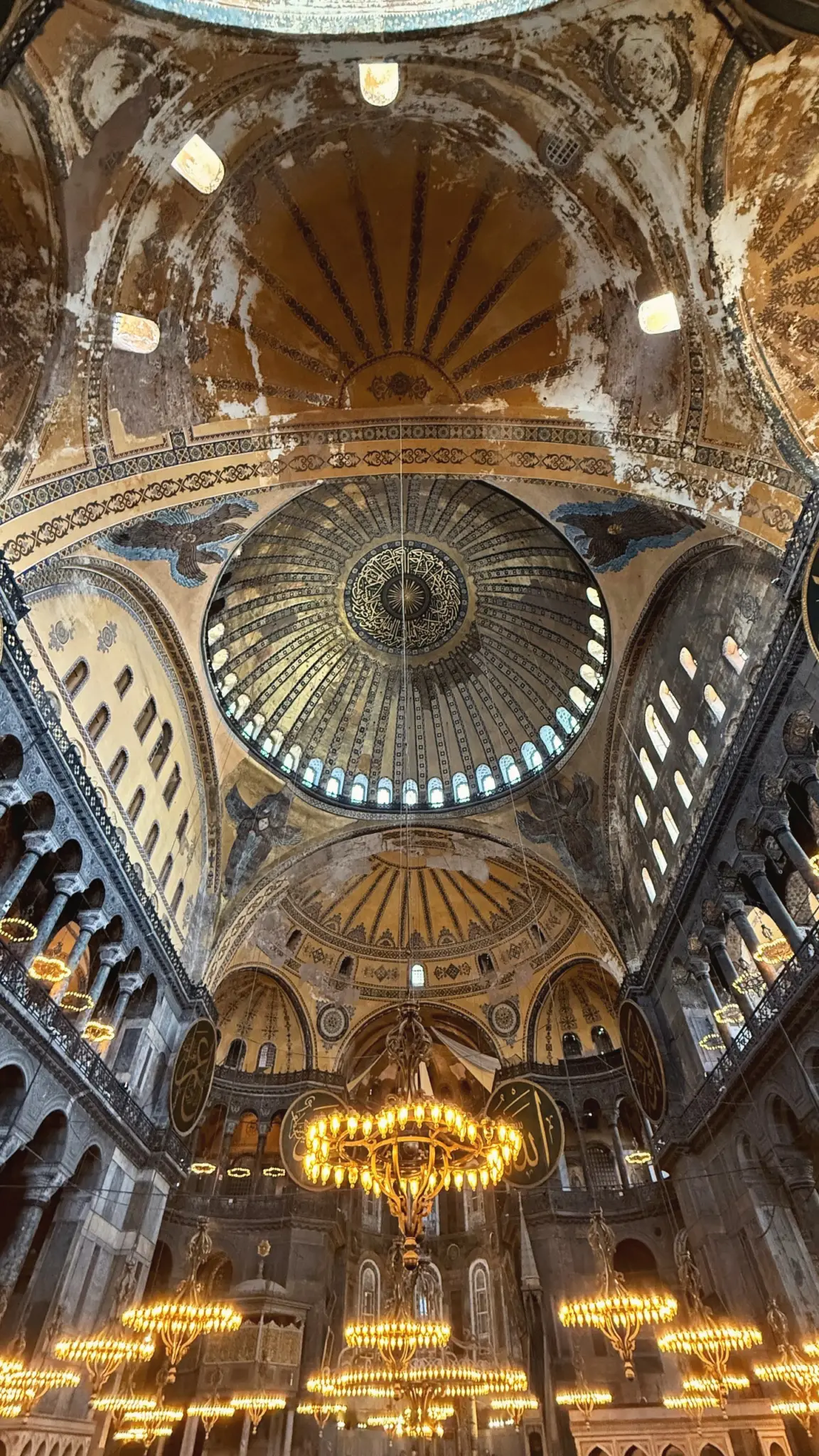 Looking up into the vast dome of Hagia Sophia above glowing chandeliers