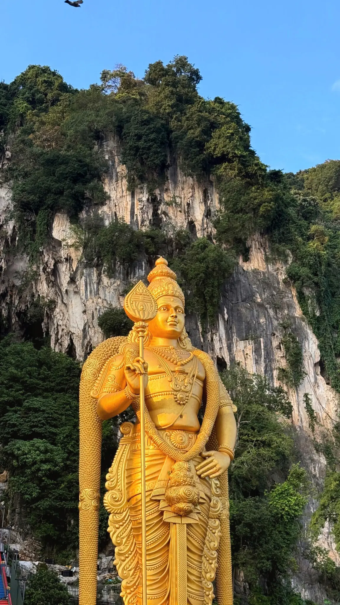 Giant golden statue of Lord Murugan before the limestone cliffs at Batu Caves