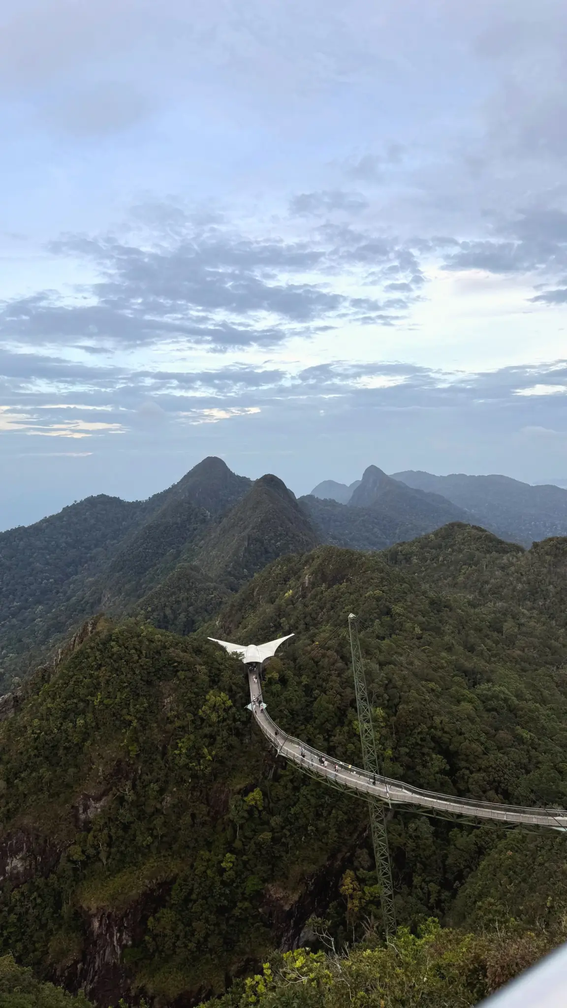 Langkawi Sky Bridge curving across a forested mountain ridge under clouds